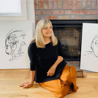 Ann Brucker posing in front of her art in a black top and gold pants.